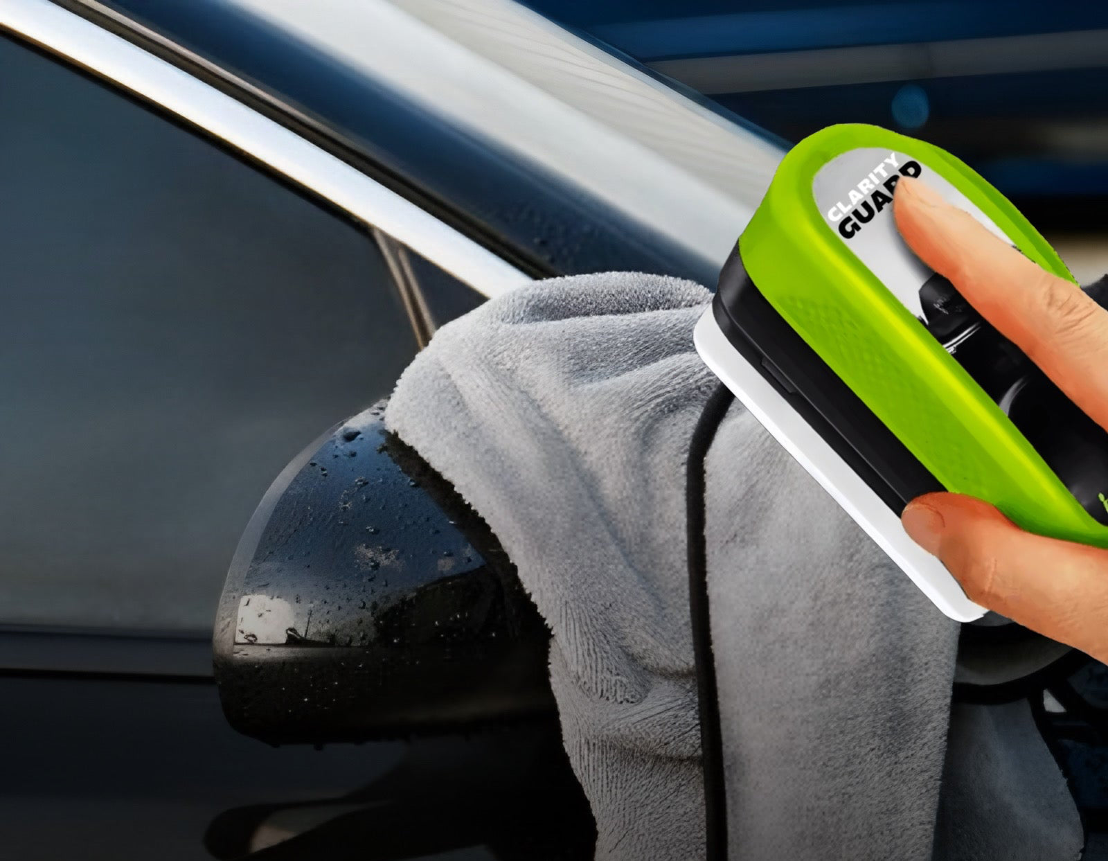 Person cleaning car window with a green squeegee and gray towel